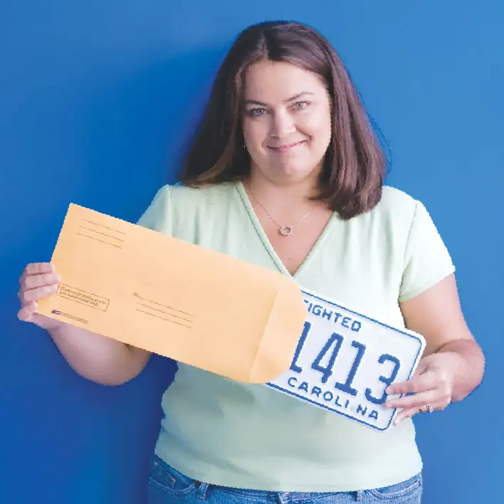 Woman holding License Plate Envelope at dealership.